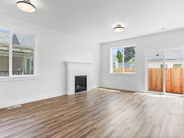 unfurnished living room featuring a brick fireplace and light hardwood / wood-style flooring