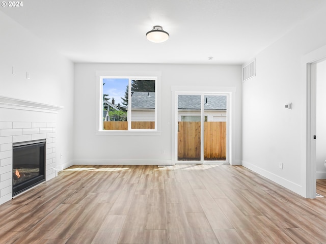 unfurnished living room featuring light hardwood / wood-style floors and a brick fireplace