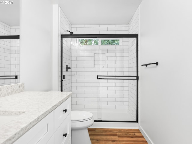 bathroom with walk in shower, hardwood / wood-style floors, vanity, and toilet