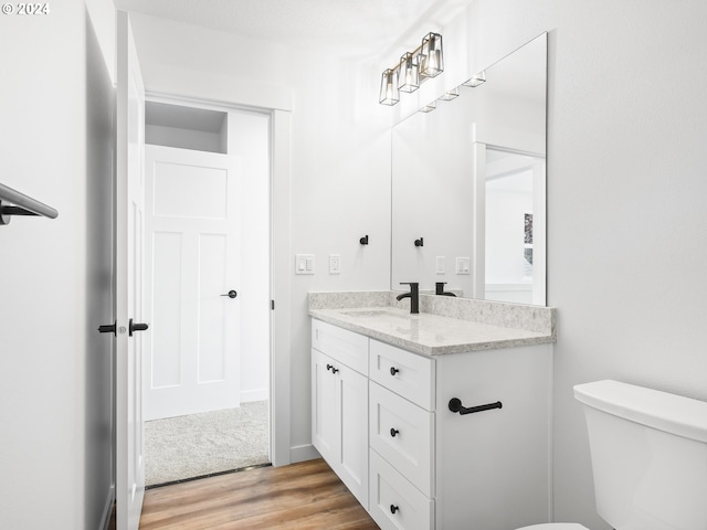 bathroom with toilet, vanity, and hardwood / wood-style flooring