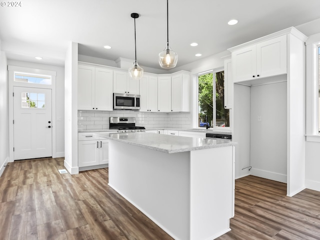 kitchen with a center island, stainless steel appliances, white cabinetry, and light stone counters