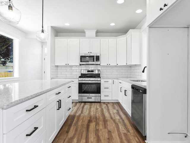 kitchen with white cabinets, stainless steel appliances, hanging light fixtures, and sink