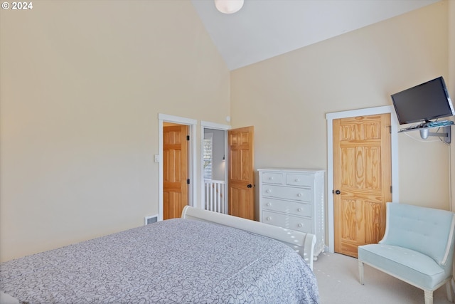 bedroom featuring light carpet and high vaulted ceiling