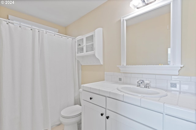 bathroom featuring vanity, toilet, and backsplash