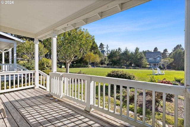 wooden deck featuring a porch and a lawn