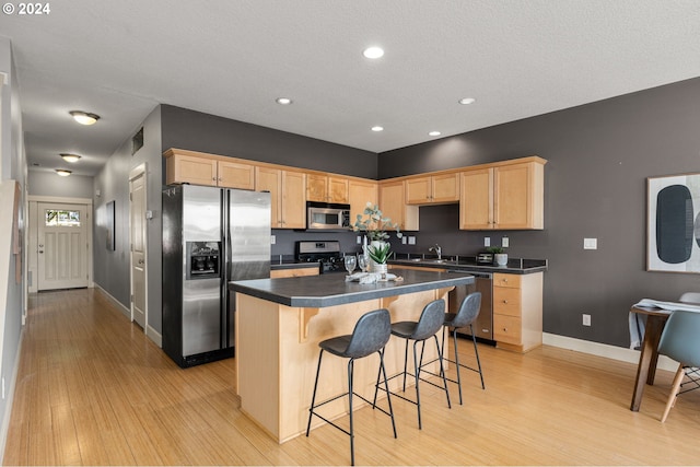 kitchen with light hardwood / wood-style floors, light brown cabinetry, a kitchen island, sink, and stainless steel appliances