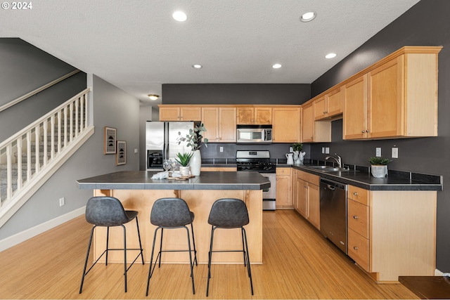 kitchen featuring light brown cabinets, appliances with stainless steel finishes, sink, and a center island