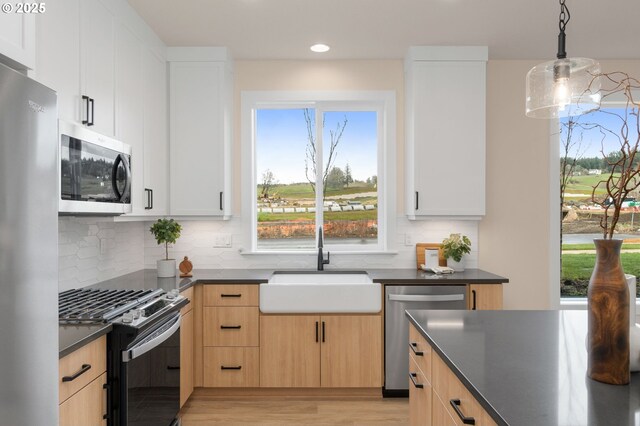 kitchen with hardwood / wood-style floors, appliances with stainless steel finishes, light brown cabinetry, and backsplash