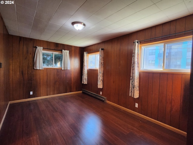 spare room with a baseboard heating unit, wooden walls, and dark hardwood / wood-style floors