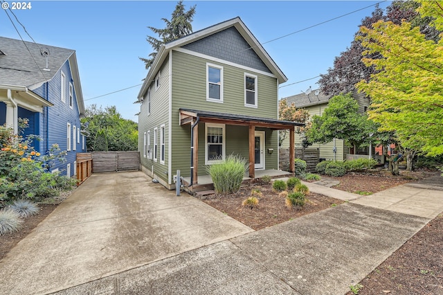 view of front of house with covered porch, driveway, and fence