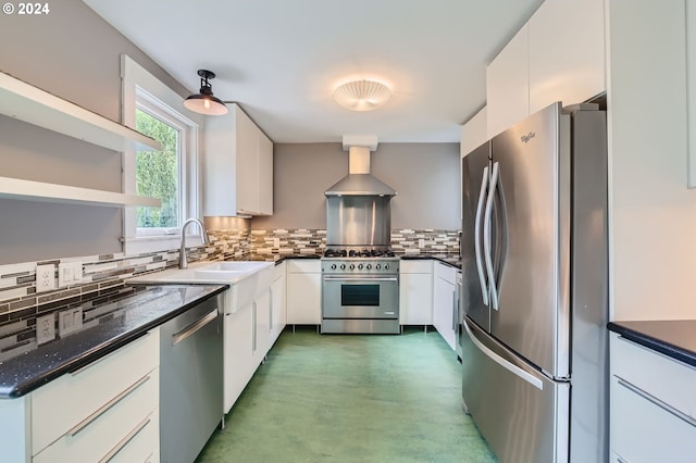 kitchen with tasteful backsplash, appliances with stainless steel finishes, white cabinetry, a sink, and wall chimney exhaust hood