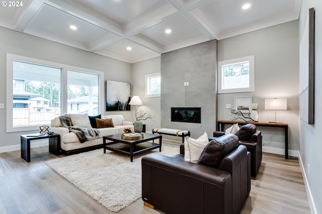 living room with coffered ceiling, a fireplace, crown molding, beam ceiling, and light hardwood / wood-style flooring