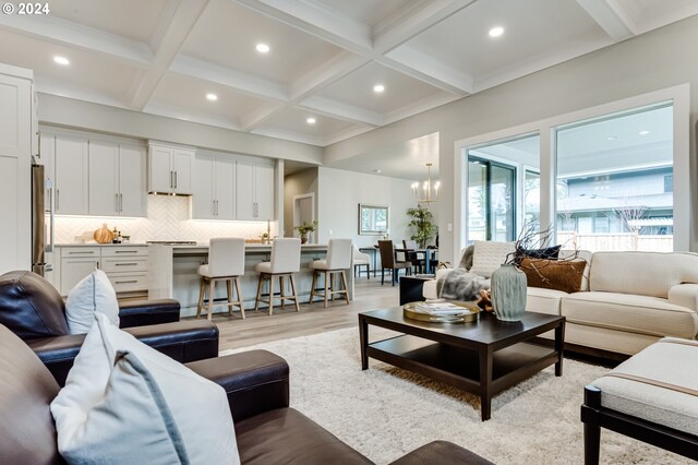 living room with light wood-type flooring, coffered ceiling, beam ceiling, and a notable chandelier