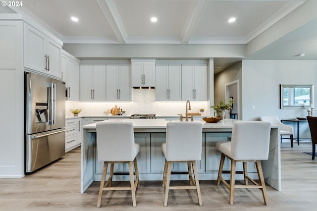 kitchen with high end refrigerator, white cabinetry, and a breakfast bar area