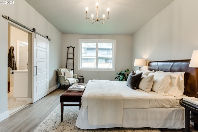 bedroom featuring light hardwood / wood-style flooring, a chandelier, and a barn door