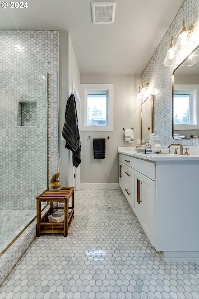 bathroom featuring a tile shower, a wealth of natural light, tile patterned floors, and vanity