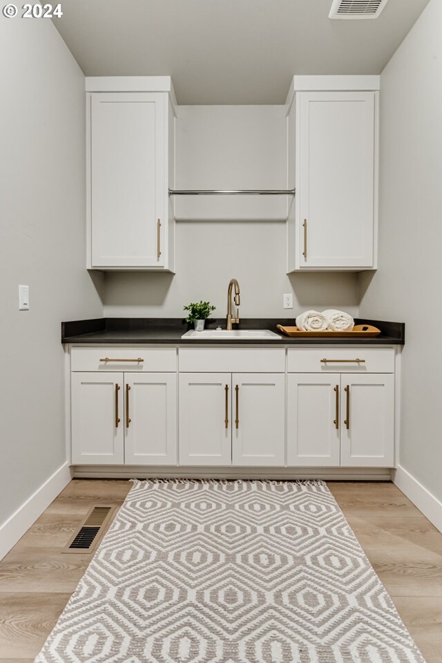 kitchen featuring light wood-type flooring, white cabinetry, and sink