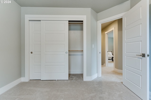 unfurnished bedroom featuring light carpet and a closet