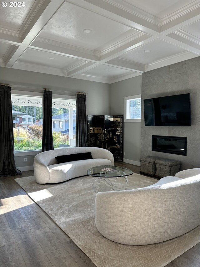 living room featuring coffered ceiling, beam ceiling, a large fireplace, hardwood / wood-style flooring, and ornamental molding