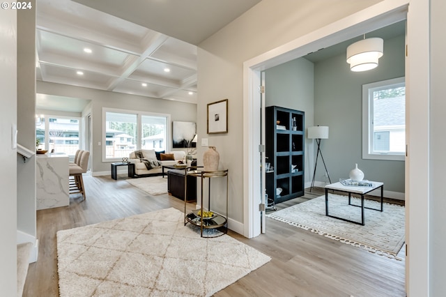 hallway with beamed ceiling, coffered ceiling, and light hardwood / wood-style flooring