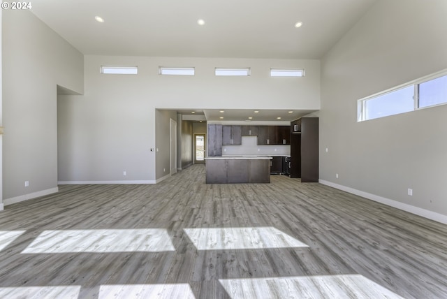 unfurnished living room with light wood-type flooring and a high ceiling