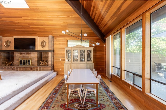 dining area featuring wood ceiling, hardwood / wood-style floors, wooden walls, a fireplace, and vaulted ceiling