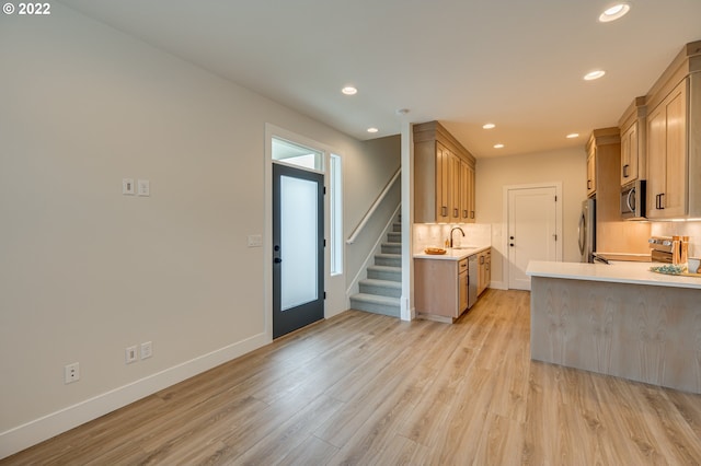 kitchen with light brown cabinets, appliances with stainless steel finishes, backsplash, and light hardwood / wood-style floors