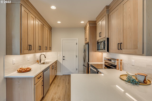 kitchen with light brown cabinets, sink, backsplash, appliances with stainless steel finishes, and light wood-type flooring