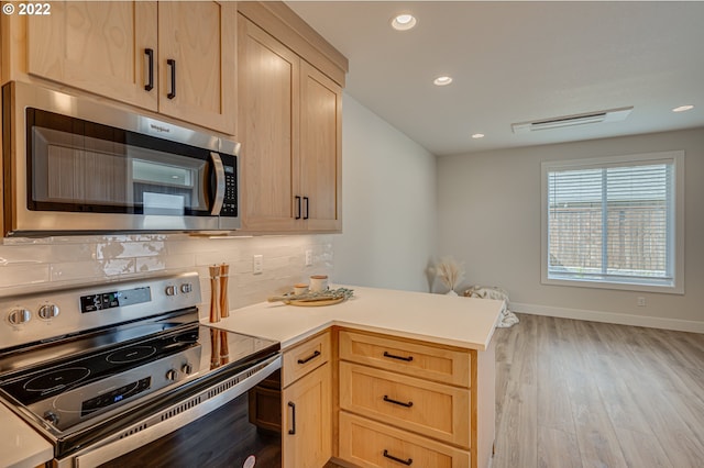 kitchen with decorative backsplash, light brown cabinets, light hardwood / wood-style flooring, and stainless steel appliances