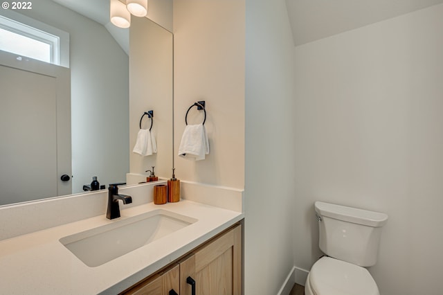 bathroom with vaulted ceiling, vanity, and toilet