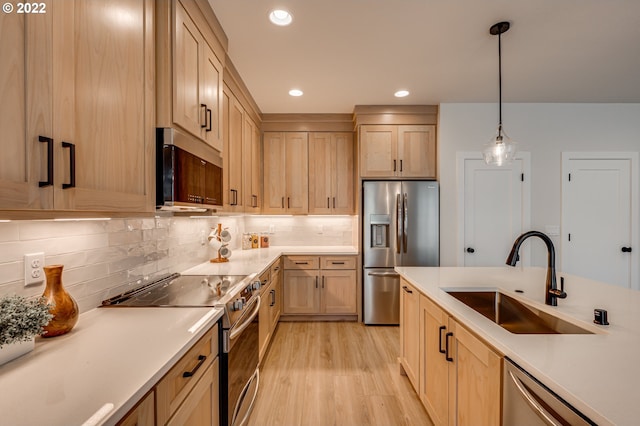 kitchen with light brown cabinetry, sink, stainless steel appliances, and decorative light fixtures