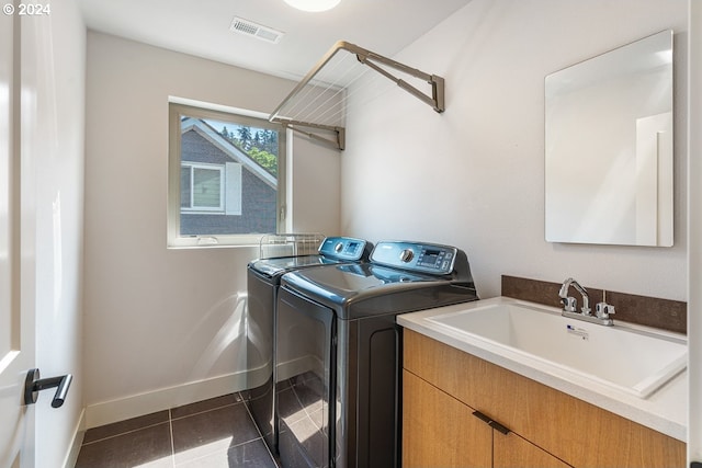 clothes washing area featuring sink, dark tile patterned floors, cabinets, and independent washer and dryer