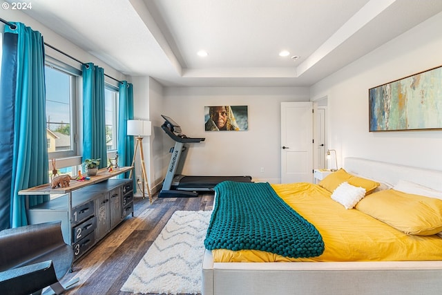 bedroom with a tray ceiling and dark hardwood / wood-style floors