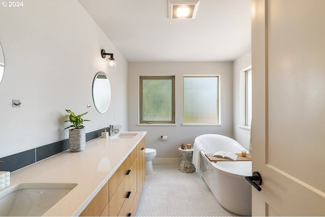 bathroom featuring tile patterned floors, vanity, toilet, and a bathing tub