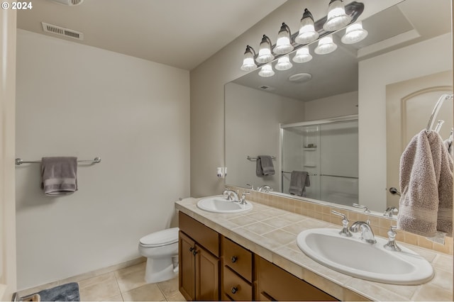 bathroom with a shower with door, vanity, toilet, and tile patterned flooring