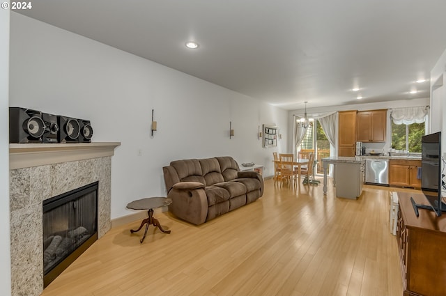 living room featuring a chandelier, a tiled fireplace, and light wood-type flooring