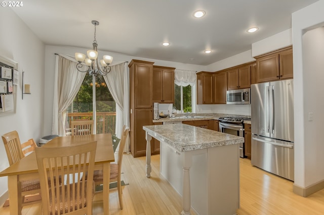 kitchen featuring a wealth of natural light, a center island, appliances with stainless steel finishes, and decorative light fixtures