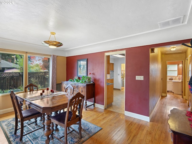 dining space with a textured ceiling and light wood-type flooring