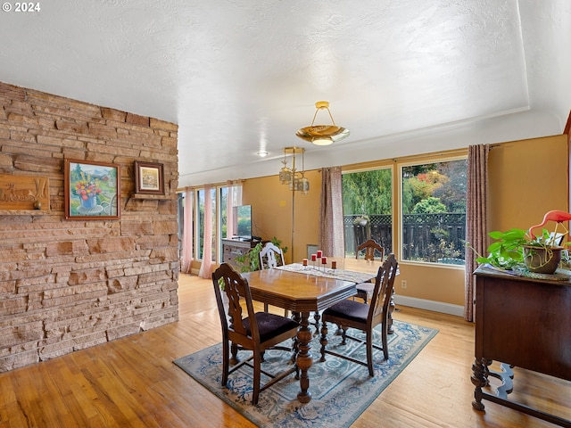 dining area featuring light wood-type flooring and a textured ceiling