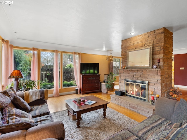 living room with light hardwood / wood-style floors and a stone fireplace