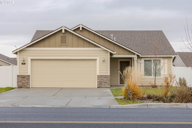 view of front facade featuring a garage, fence, driveway, roof with shingles, and board and batten siding