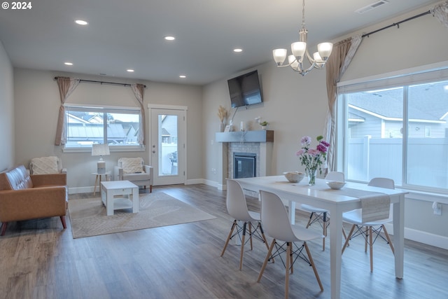 dining space featuring recessed lighting, visible vents, a glass covered fireplace, wood finished floors, and baseboards