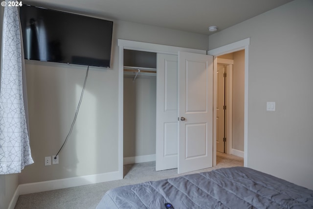 carpeted bedroom with a closet and baseboards