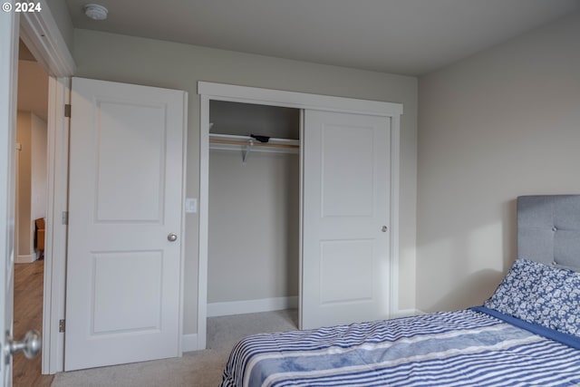 carpeted bedroom with baseboards and a closet