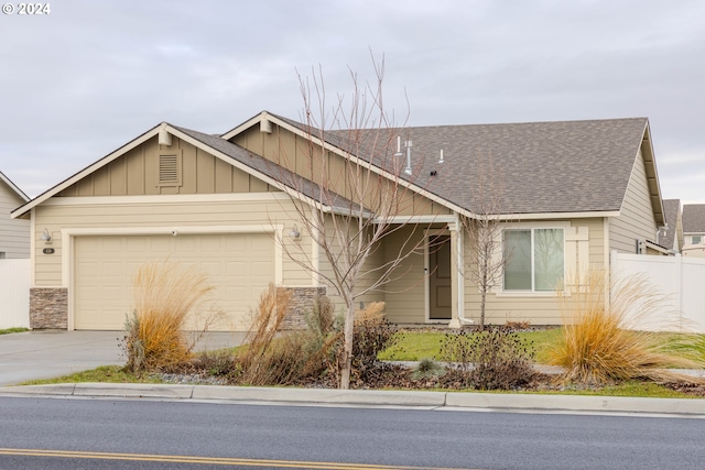 view of front of house featuring an attached garage, a shingled roof, fence, driveway, and board and batten siding