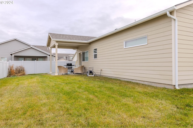 rear view of house with a yard, a patio, and fence