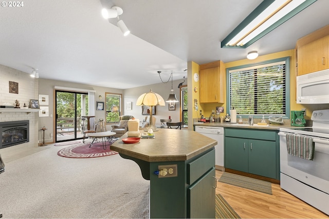 kitchen featuring white appliances, light wood-type flooring, a fireplace, green cabinets, and a center island