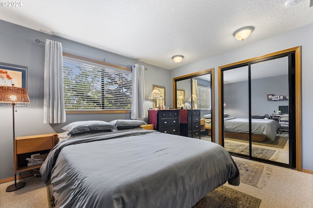 bedroom featuring carpet floors, multiple closets, and a textured ceiling