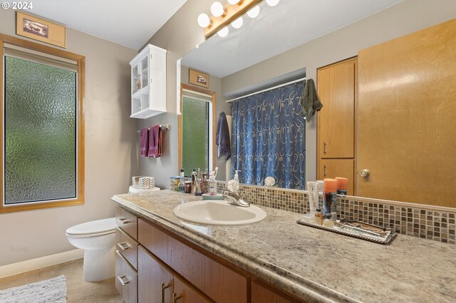 bathroom with backsplash, vanity, toilet, and tile patterned floors