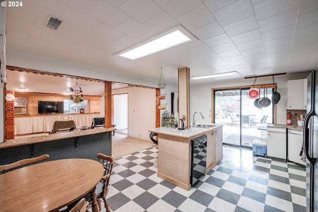 kitchen with light tile patterned floors, white cabinets, a kitchen island with sink, pendant lighting, and sink